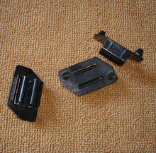 Carica l'immagine nel visualizzatore di Gallery, Two black W-shaped plastic button retainers with metal slots, angled view