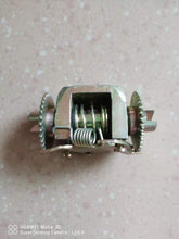 Cargar imagen en el visor de la Galería, Rear brake adjusting assembly viewed from side, showing central spring and toothed wheels