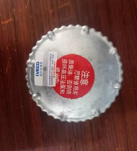 Load image into Gallery viewer, Circular fuel tank cap with serrated metal edge and red label on underside
